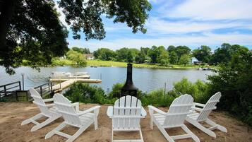 Une vue sur le lac, avec un quai, des chaises Adirondack blanches et une cheminée.