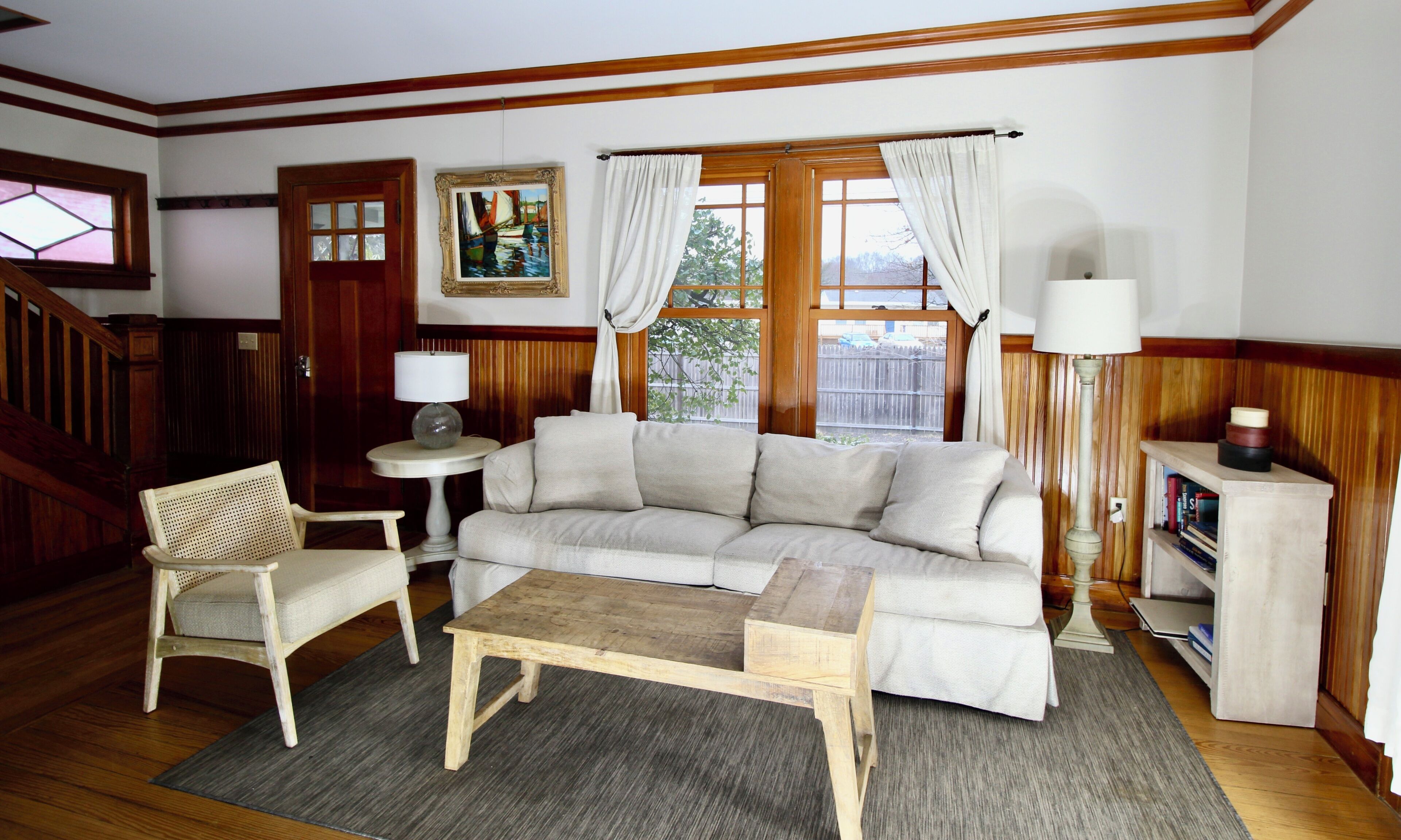 Un salon avec un canapé, une petite table, une chaise, une lampe et un tableau accroché au mur.
