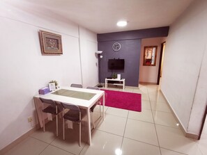 Een moderne woonkamer met een eethoek, een flatscreen televisie, een klok en een rood vloerkleed.