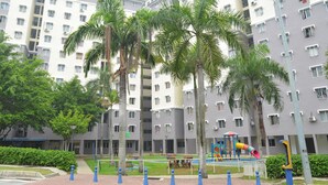 A multi-story residential building with balconies, a playground, and palm trees. - iCheck Homestay Putrajaya (Putrajaya)