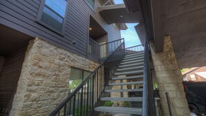Eine Treppe führt zu einem Balkon mit Steinmauern und einem Metallgeländer.