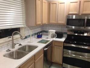 A kitchen with a stainless steel sink, a coffee maker, a toaster, and a microwave.