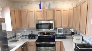 A kitchen with wooden cabinets, a stainless steel microwave, a double oven, and a coffee maker. - Pet friendly  See specials in the description section (Nags Head)