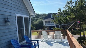 A wooden deck with two Adirondack chairs and a lantern on a house's exterior wall. - Pet friendly  See specials in the description section (Nags Head)