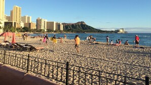 Una playa con gente, sombrillas y un paisaje urbano al fondo.