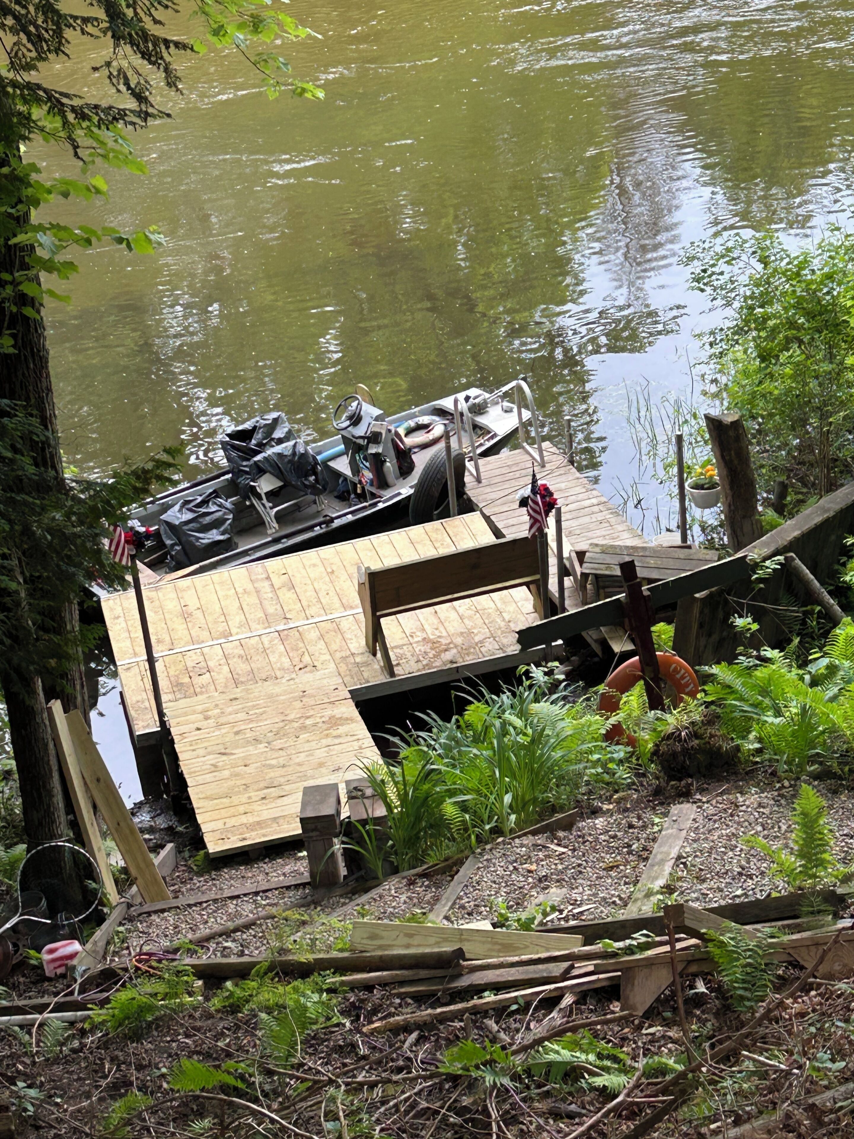 Une jetée en bois s’étendant dans une étendue d’eau, entourée de verdure.