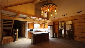 Een ruime keuken met een centraal eiland, houten balken en een hanglamp.