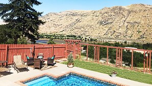 A backyard with a swimming pool, patio furniture, and a view of a lake and mountains. - Lake Chelan: Private Pool, Hot Tub, Stunning Views, 7 Mins to Chelan Sleeps 6 (Chelan Falls)