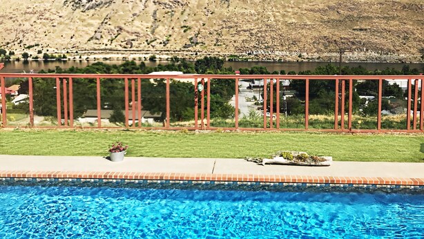 A swimming pool with a view of a mountainous landscape and a red metal fence. - Lake Chelan: Private Pool, Hot Tub, Stunning Views, 7 Mins to Chelan Sleeps 6 (Chelan Falls)
