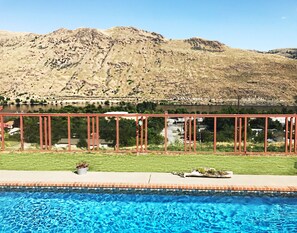 A swimming pool with a view of a mountainous landscape and a red metal fence.