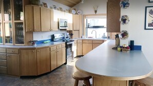 A kitchen with wooden cabinets, a central island, and a microwave. - Lake Chelan: Private Pool, Hot Tub, Stunning Views, 7 Mins to Chelan Sleeps 6 (Chelan Falls)