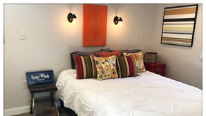 A neatly made bed with white bedding, a small side table with a box labeled "Handy Andy Tool Set," and a red nightstand with a lamp. - Lake Chelan: Private Pool, Hot Tub, Stunning Views, 7 Mins to Chelan Sleeps 6 (Chelan Falls)