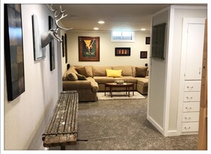 A living room with a sectional sofa, a coffee table, a bench, and a cabinet.