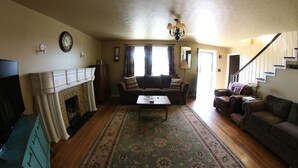 A living room with a fireplace, sofa, coffee table, and a staircase. - Awesome Flat Top Farmhouse - Ashwood Rentals (Flat Top)