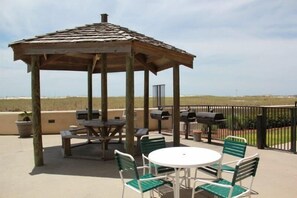 A gazebo with a table and chairs, outdoor grills, and a view of the beach. - Phoenix VII 71113 by ALBVR - Upgraded Beautiful Beachfront Condo Could be Yours! (Orange Beach)