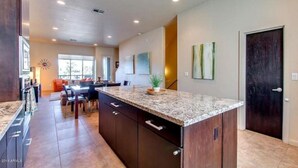 A spacious kitchen with dark wood cabinets, a granite countertop, and a large island.