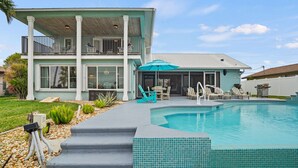 A two-story house with a swimming pool, outdoor seating, and a covered patio area. - Pool, Spa, Kayaks, Bikes, Fishing Gear & More waterfront, Amenities at no charge (Cape Coral)