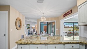 A kitchen with a granite countertop, white cabinetry, and a sign reading "Beach House". - Pool, Spa, Kayaks, Bikes, Fishing Gear & More waterfront, Amenities at no charge (Cape Coral)