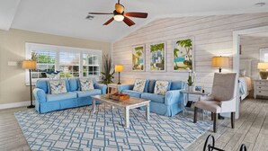 A living room with a blue sofa set, a coffee table, and a ceiling fan. - Pool, Spa, Kayaks, Bikes, Fishing Gear & More waterfront, Amenities at no charge (Cape Coral)