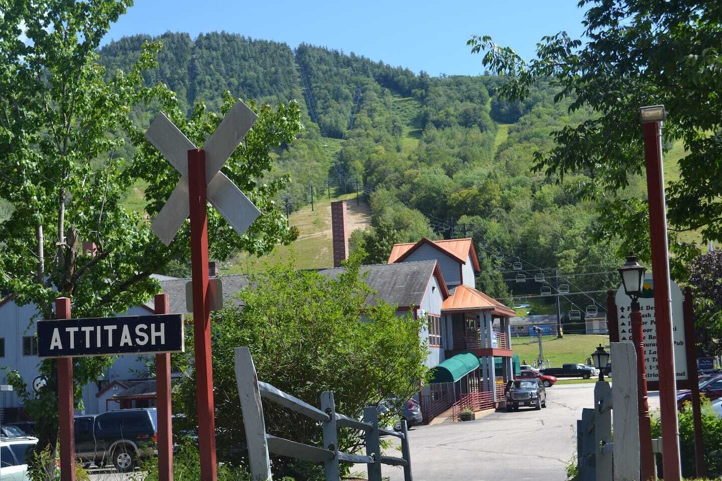 A railway crossing sign with 'ATTITASH' and a small building with a green awning.