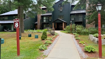A building with a green exterior, a covered entrance, and a pathway leading to the entrance.