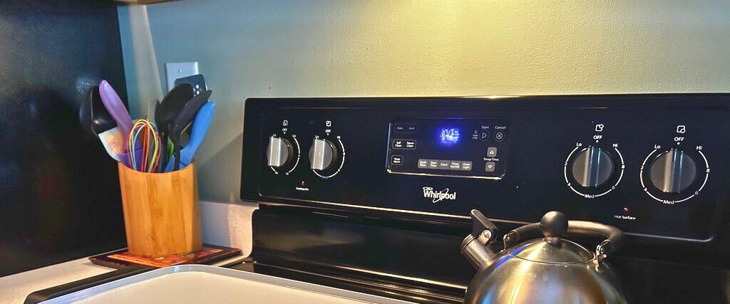 Una cocina con estufa Whirlpool, un hervidor y un organizador de utensilios.
