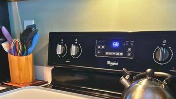 Una cocina con estufa Whirlpool, un hervidor y un organizador de utensilios.