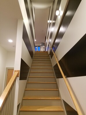 Een trap met houten leuningen en een modern ontwerp, die uitkomt in een kamer met uitzicht.
