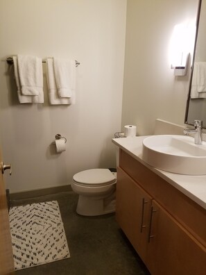 A bathroom with a toilet, sink, mirror, and towels.