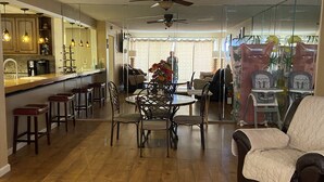 Ein geräumiger Wohnbereich mit Holzboden, einem Esstisch mit Stühlen, einer Couch und einer Küchenzeile mit Bar und Hockern.