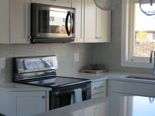 Une cuisine moderne dotée d’appareils électroménagers en acier inoxydable, de meubles blancs et d’un dosseret en carreaux disposés en motif chevron.