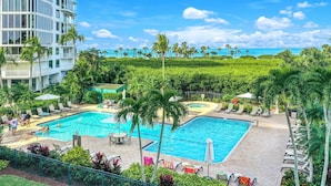 Un resort con varias piscinas, palmeras y vistas al océano.