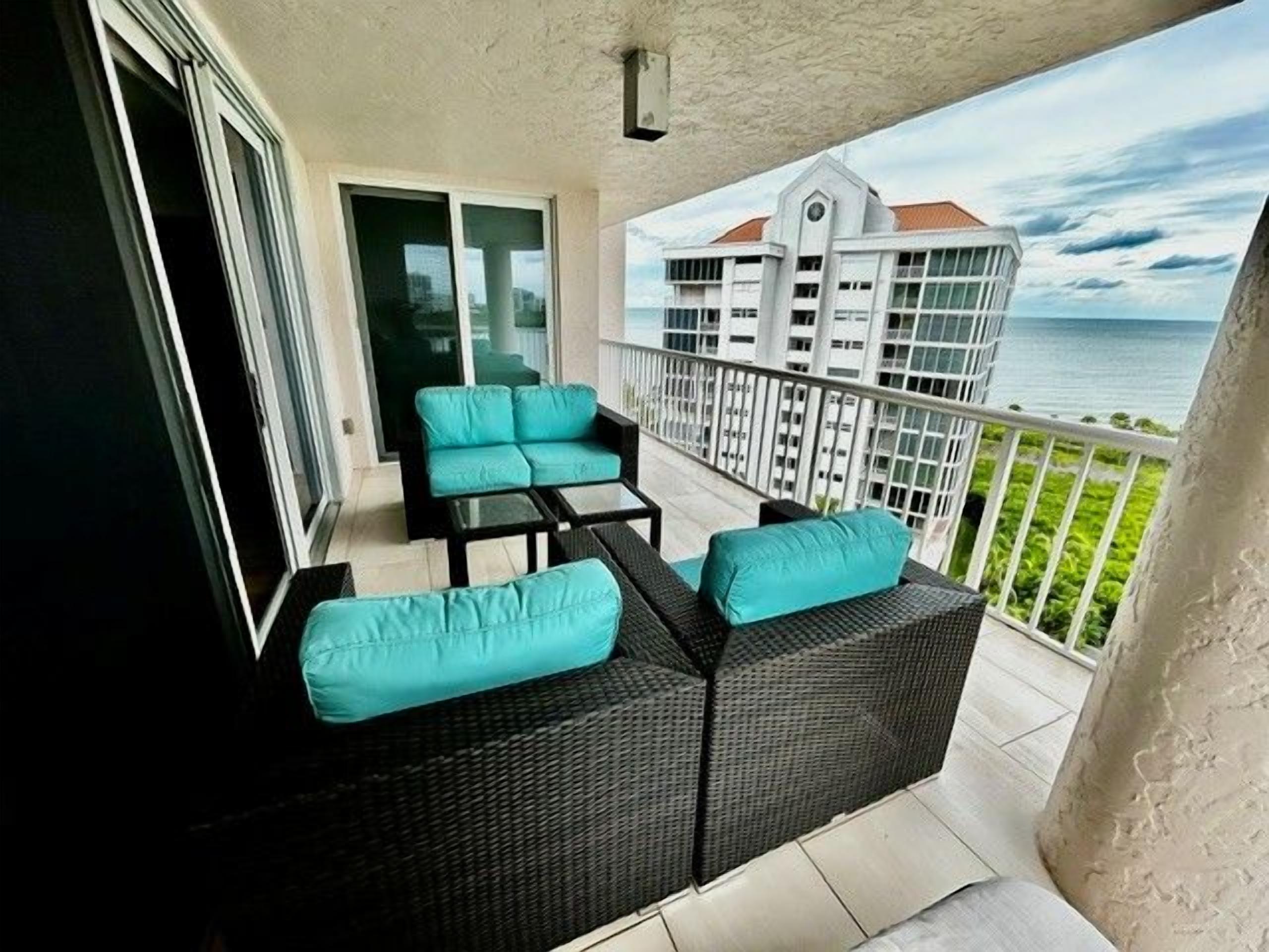 Ein Balkon mit Gartenmöbeln, Blick auf das Meer und ein Gebäude im Hintergrund.