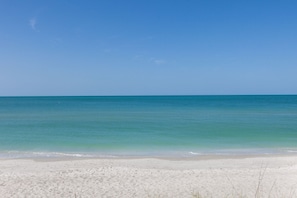 Enjoy a serene beach experience with a tranquil sea and soft sand.