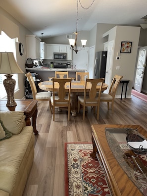 A dining area with a wooden table and chairs, a kitchen in the background, and a patterned rug on the floor. - Located in Beautiful Country Club of Mount Dora (Mt Dora)