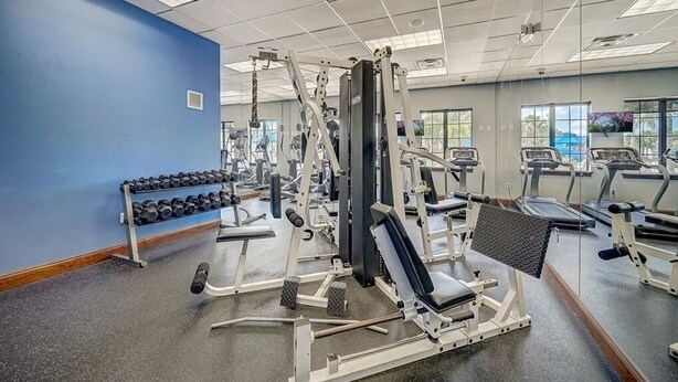 Une salle de sport équipée de divers appareils d’exercice, d’une série de haltères et de tapis de course.
