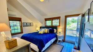 A bedroom with a large bed, two bedside tables, a wooden bench, and a view of the outdoors. - Madaket Beach House- Walk to Beach- Private Nantucket Home. (Nantucket)