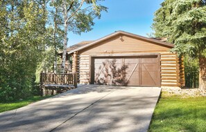 Stylish log cabin with a central gable roof and front porch, set amidst a serene natural setting.