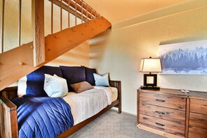 Cozy retreat with a plush bed, dresser, and framed artwork.