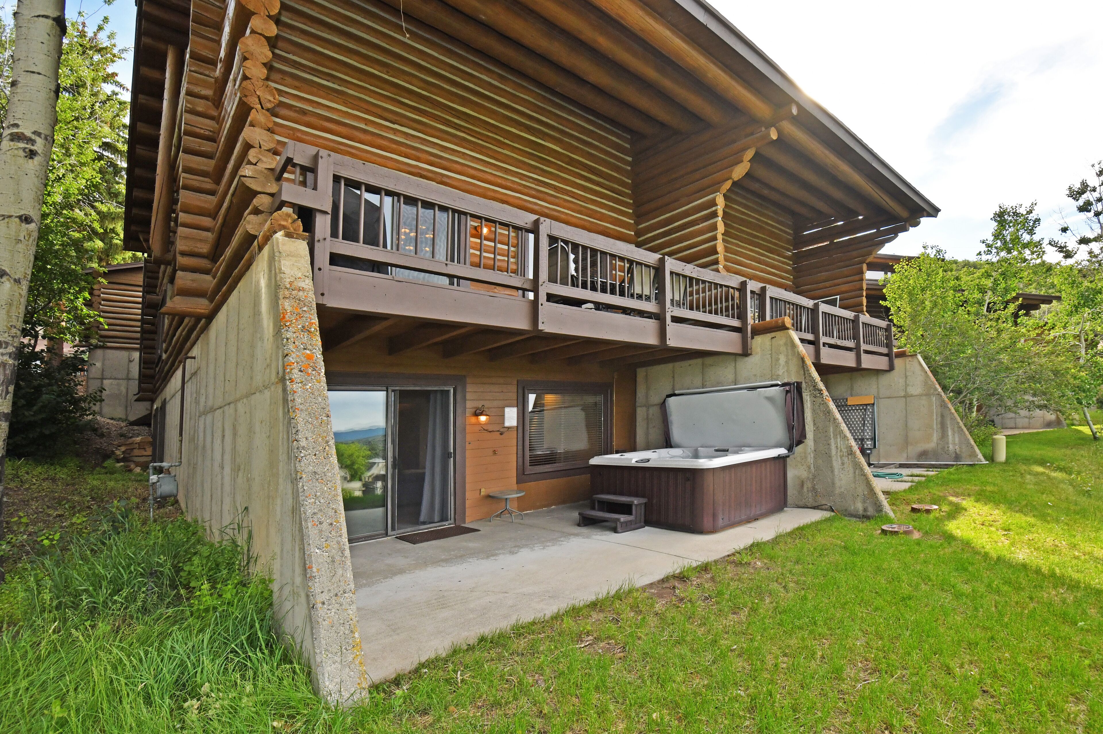 Eine Blockhütte mit Balkon, Whirlpool und einer Steinmauer.