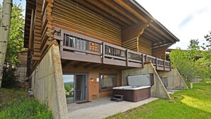 Eine Blockhütte mit Balkon, Whirlpool und einer Steinmauer.