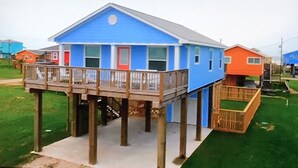 Ein zweistöckiges Haus mit blauer Fassade und einer Holzterrasse.