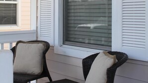 Eine Veranda mit zwei Korbstühlen und einem Fenster mit Rollläden.