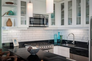 A modern kitchen with white cabinetry, a stainless steel stove, and a built-in microwave. - Coco Azul -Beach Front- Ocean Front-No Stairs (Puerto Vallarta)
