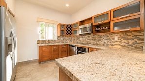 A modern kitchen with granite countertops, wooden cabinets, and a built-in microwave. - Oceanfront Oasis Close to Beach w/ Two Pools (Huatulco)