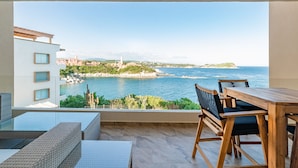A balcony with a wooden table and chairs, overlooking a coastal view with buildings and a clear sky. - Oceanfront Oasis Close to Beach w/ Two Pools (Huatulco)