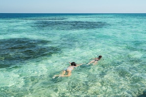 Deux personnes nagent dans une eau turquoise et cristalline.