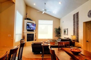 A living room with a TV, fireplace, dining table, chairs, and a ceiling fan. - 3 KING BEDS Highest rated Moab Rim Village S1 (Grand County)