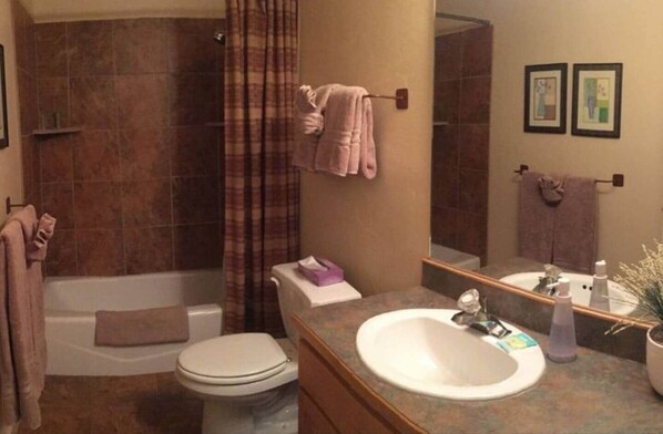 A bathroom with a bathtub, toilet, sink, and shower curtain.