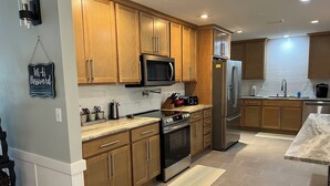 A modern kitchen with wooden cabinets, stainless steel appliances, and a marble countertop.